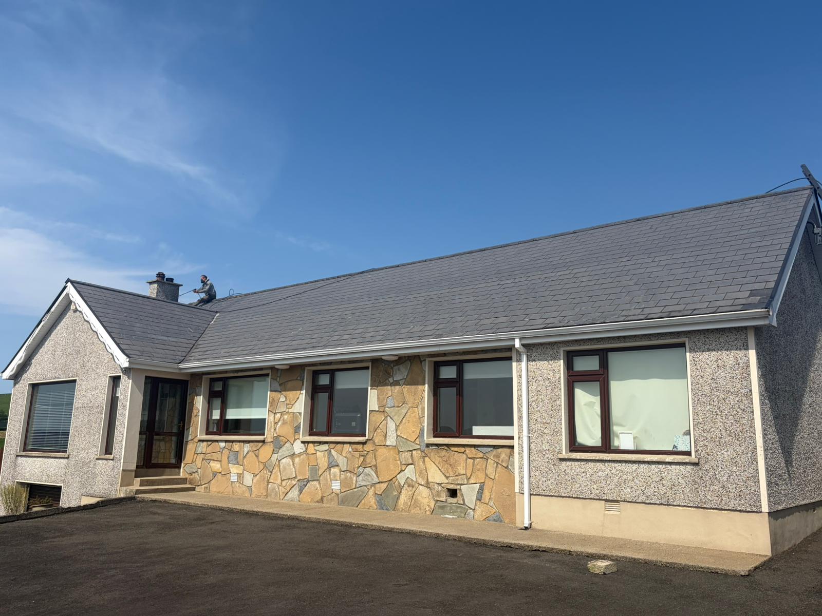 Worker spraying slate roof on residential property